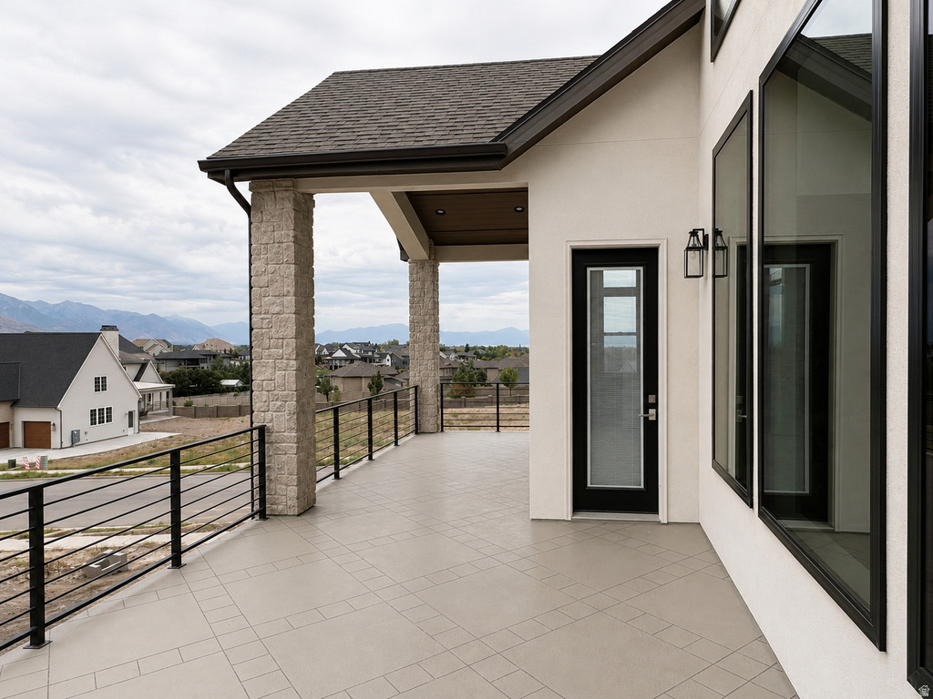 Covered outdoor balcony featuring stone-clad pillars, black metal railings, and a tiled surface