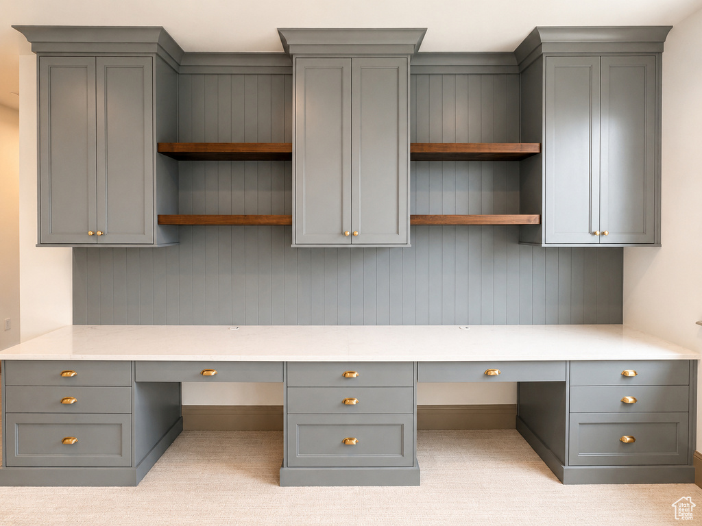 Built-in cabinetry with a paneled back wall, quartz countertops, rich wood-finish open shelving, and brass hardware