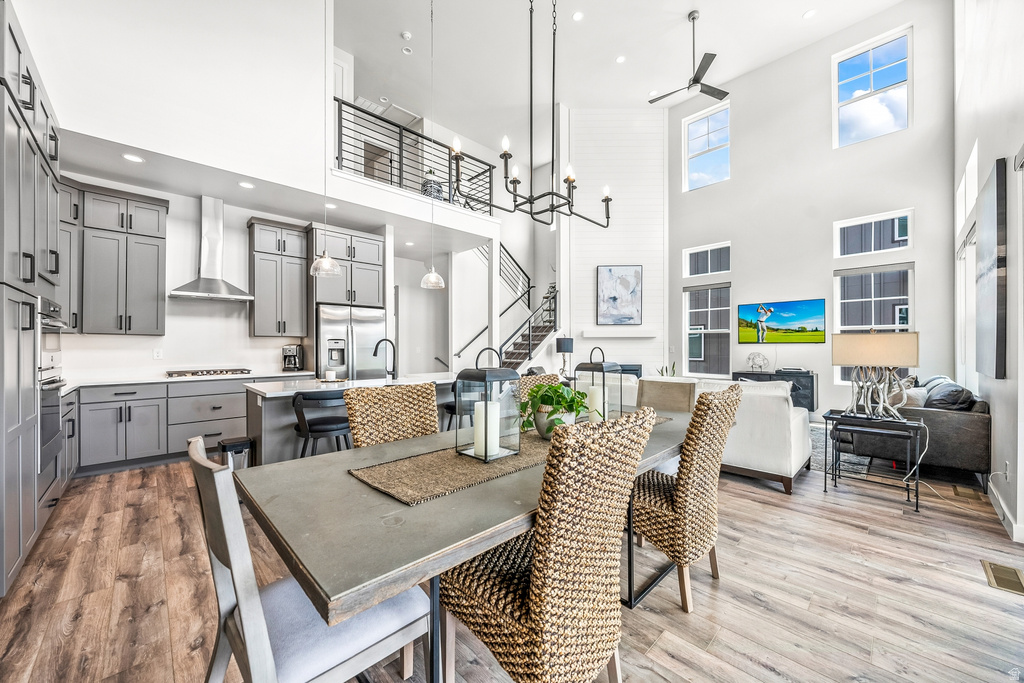 Dining space with a high ceiling, light wood finished floors, ceiling fan, and suspended lighting