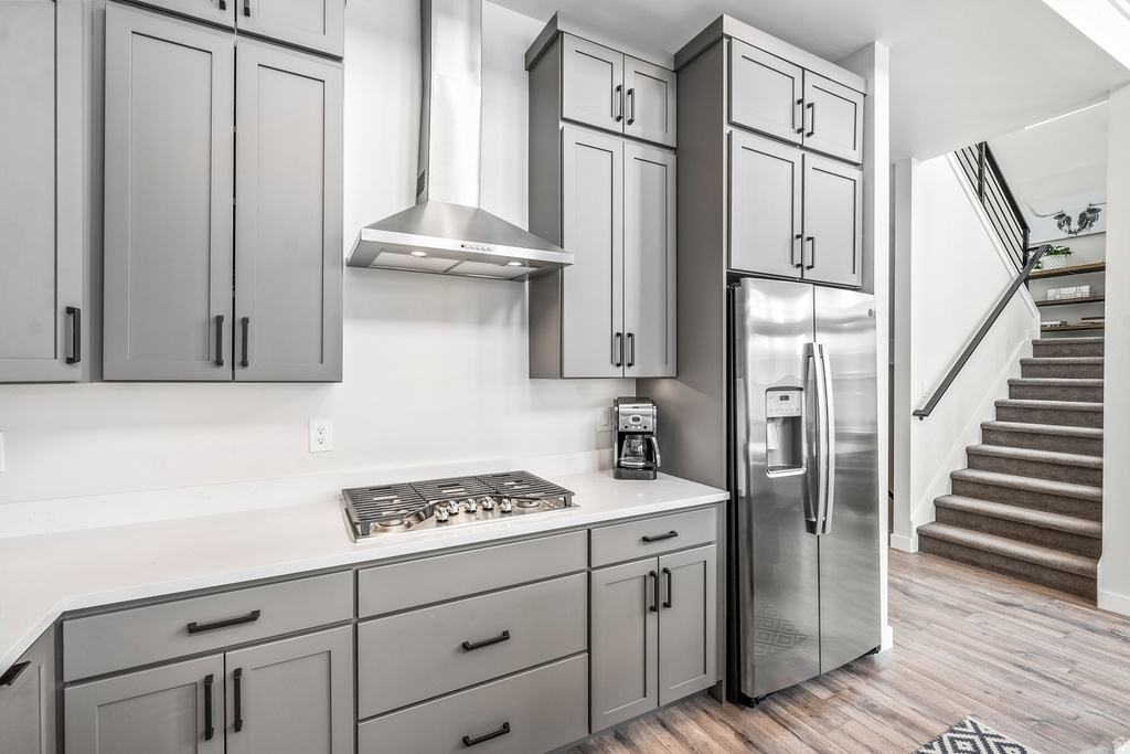 Kitchen featuring gray cabinetry, stainless steel appliances, light wood finished floors, and light stone counters