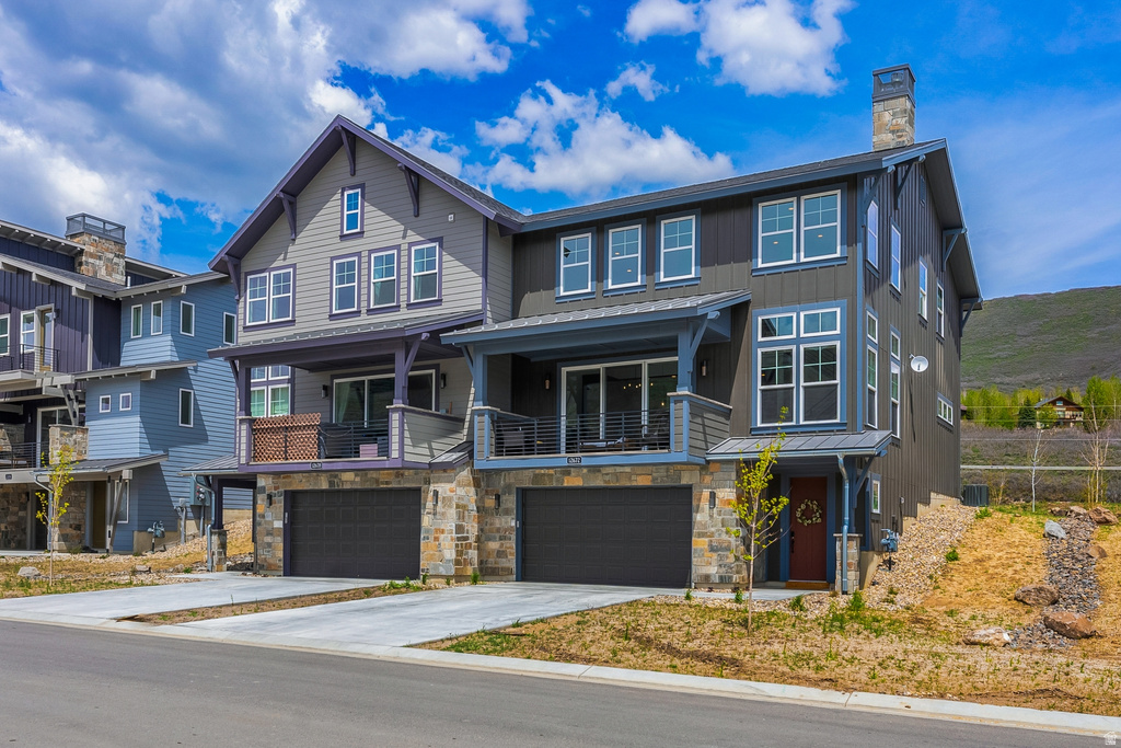 View of front of house featuring concrete driveway, an attached garage, stone siding, and a chimney