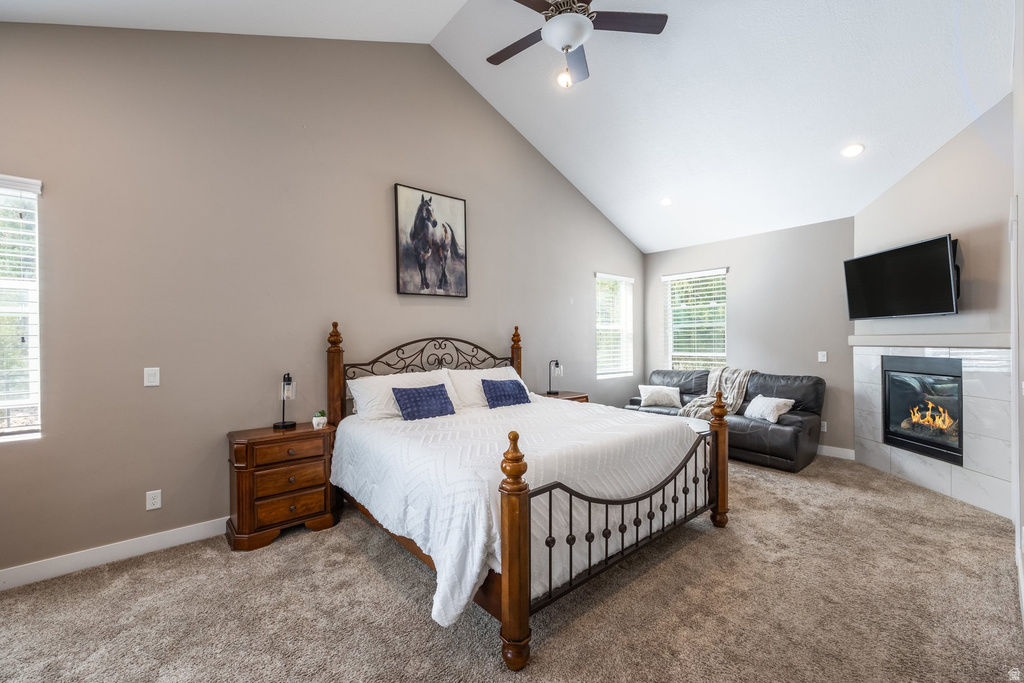 Bedroom featuring lofted ceiling, carpet, a tile fireplace, and ceiling fan