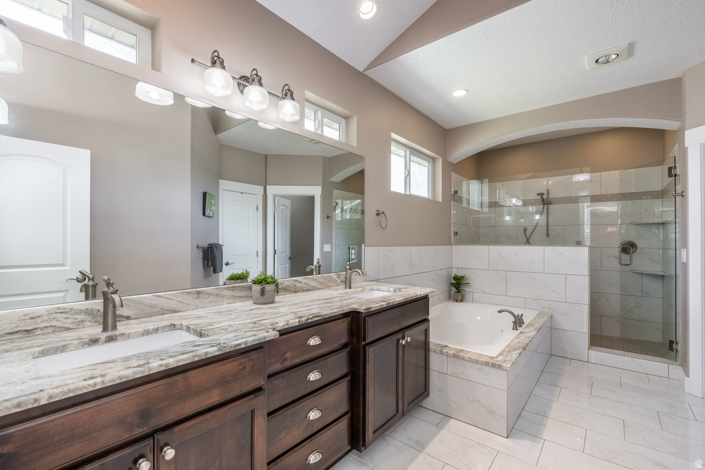 Full bathroom featuring a shower stall, double vanity, and a garden tub