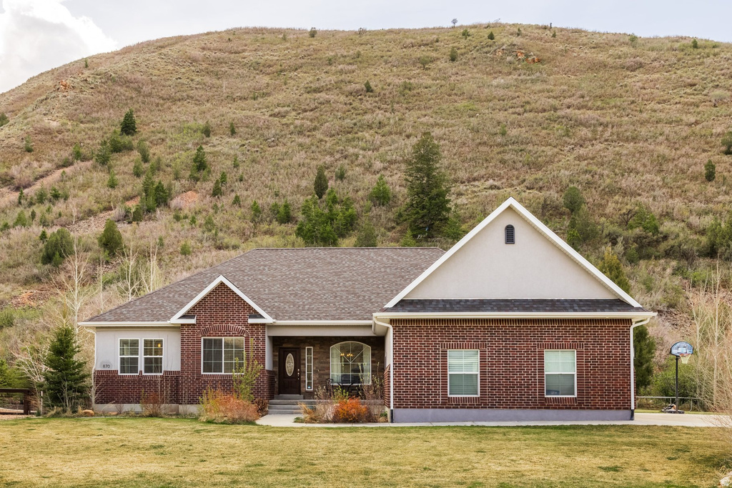 Ranch-style house with a porch, a front lawn, brick siding, and a shingled roof