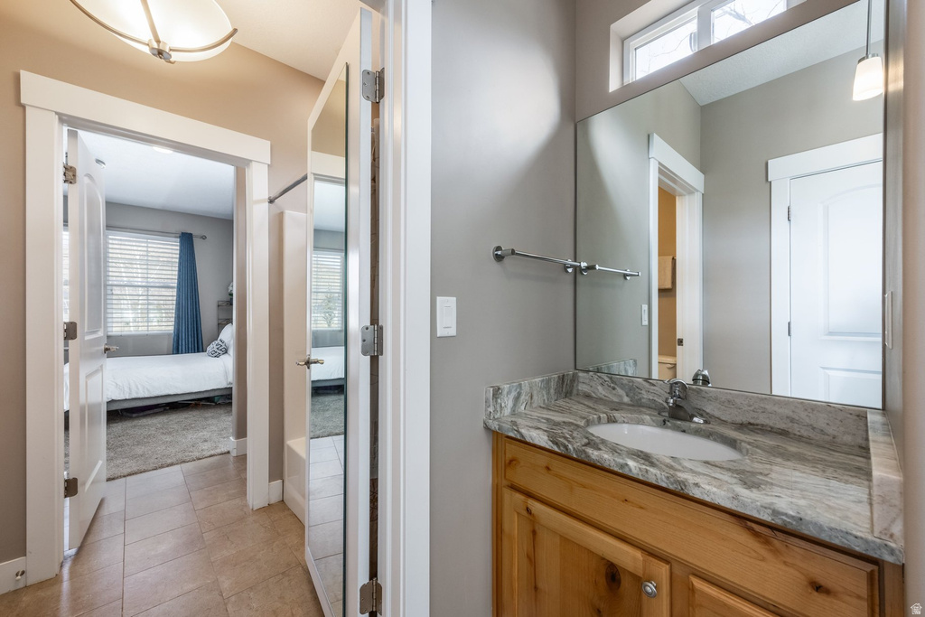 Full bath featuring connected bathroom, vanity, and light tile patterned floors