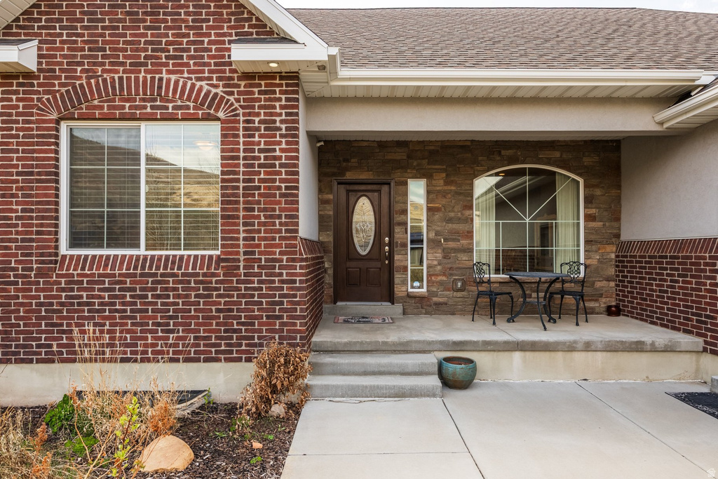 Doorway to property with a porch and brick siding