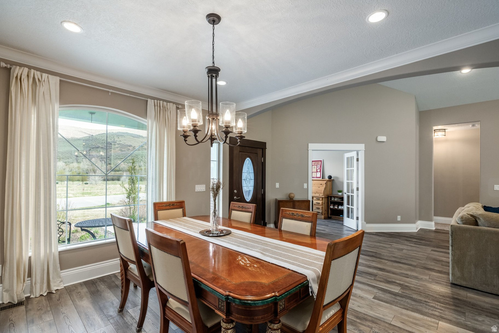 Dining space featuring lofted ceiling, arched walkways, dark wood-type flooring, and plenty of natural light