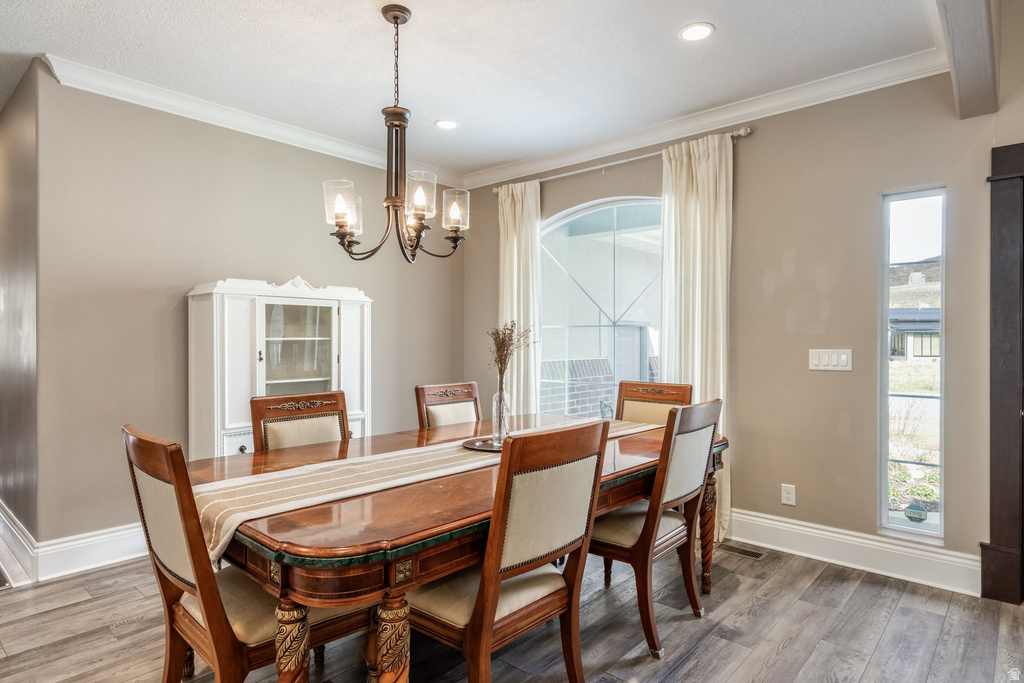 Dining area featuring ornamental molding, wood finished floors, and hanging lights