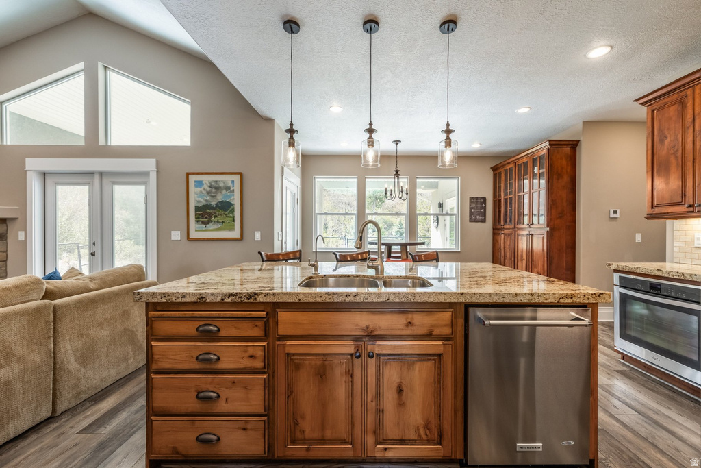 Kitchen with wood finish cabinets, a kitchen island with sink, stainless steel appliances, dark wood-style floors, and open floor plan