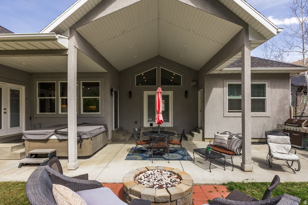 View of patio / terrace featuring outdoor dining space, a fire pit, a hot tub, a grill, and french doors