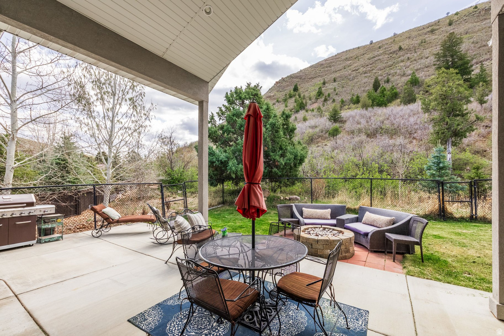 Fenced backyard featuring a fire pit, a patio, an outdoor living / dining area, and grilling area