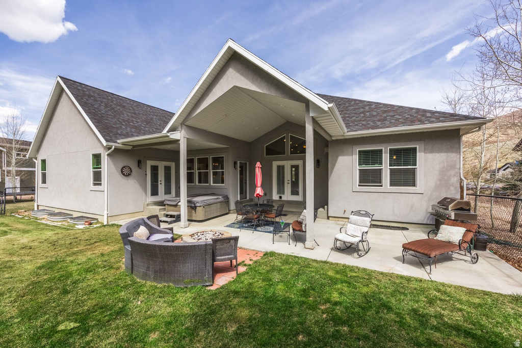 Back of house featuring french doors, a shingled roof, stucco siding, and a hot tub
