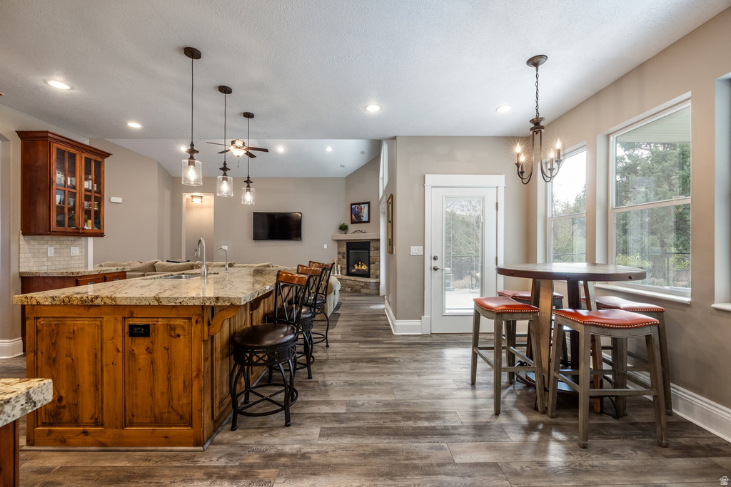 Kitchen featuring glass fronted cabinets, wood finish cabinets, a fireplace, and light stone countertops