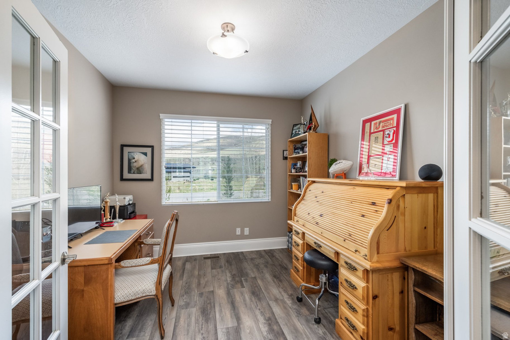 Home office with dark wood-style floors and a textured ceiling