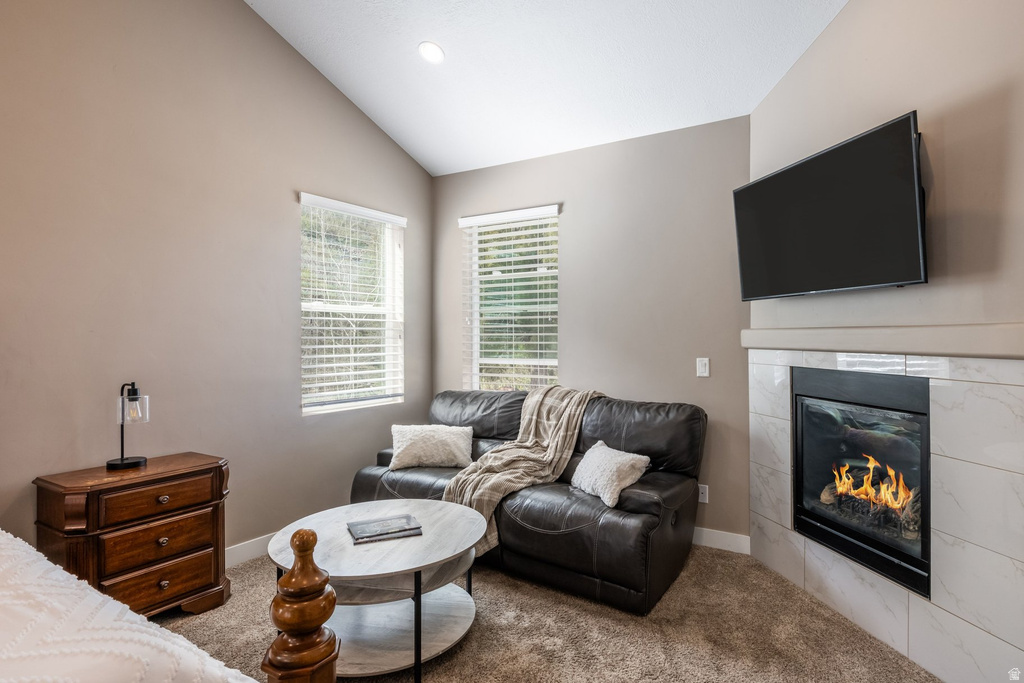 Carpeted living area with vaulted ceiling and a tiled fireplace