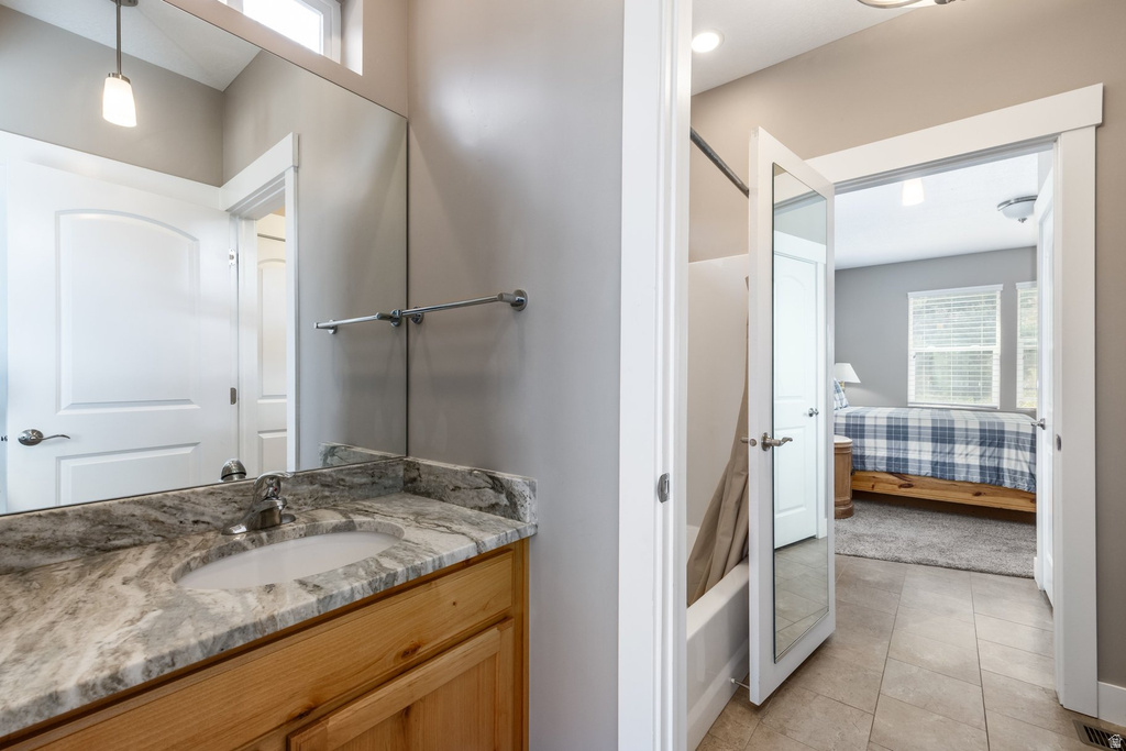 Bathroom with plenty of natural light, vanity, light tile patterned floors, and ensuite bath