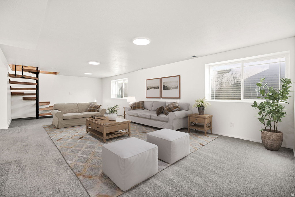 Spacious living area featuring light gray carpet, multiple windows, a spiral staircase with wood treads, recessed lighting, and white walls