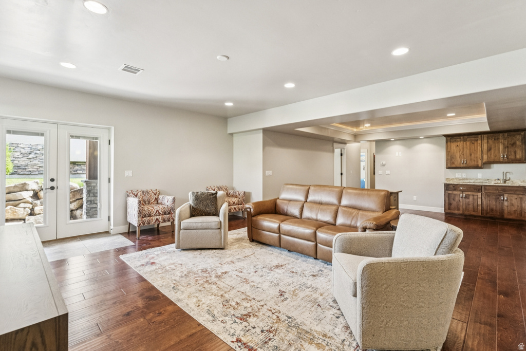 Living area with a tray ceiling, french doors, recessed lighting, and dark wood finished floors