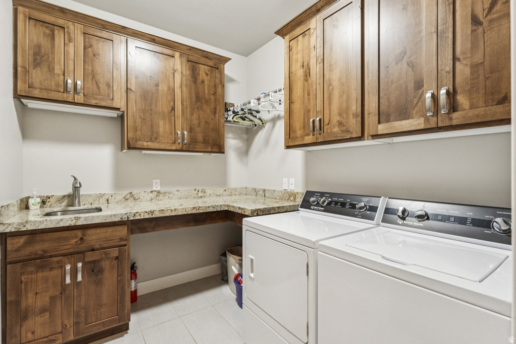 Laundry room with washer and clothes dryer, cabinet space, and light tile patterned floors