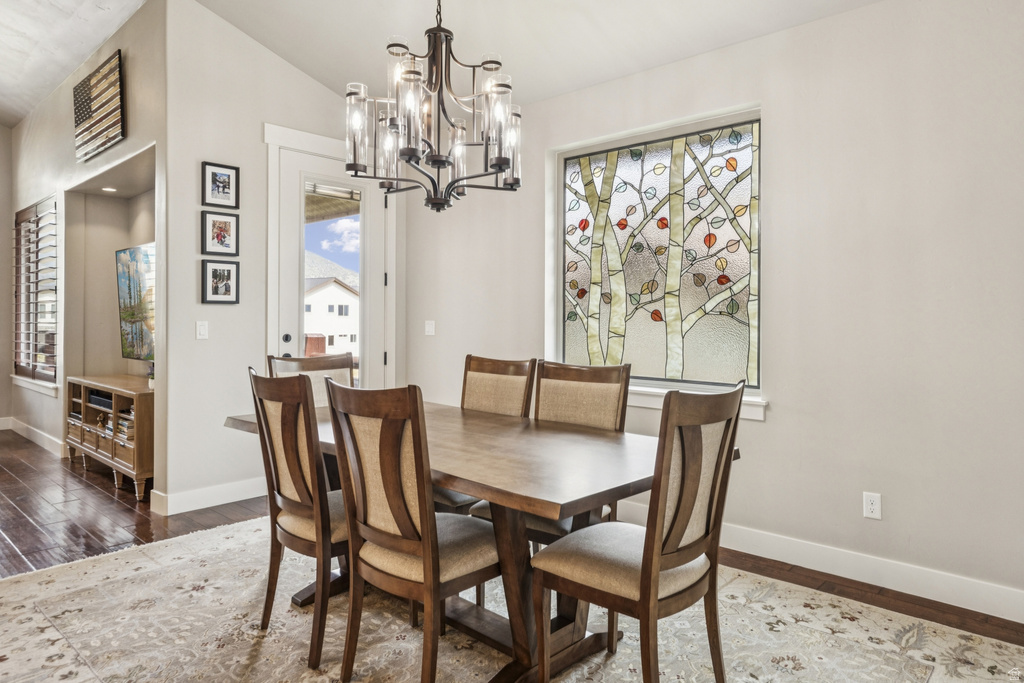 Dining room with wood finished floors, a chandelier, and lofted ceiling
