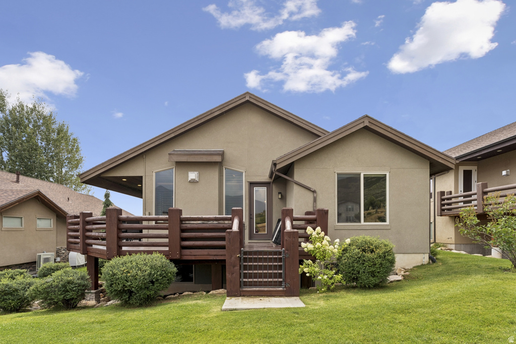 View of front of property with a front lawn, stucco siding, and a deck