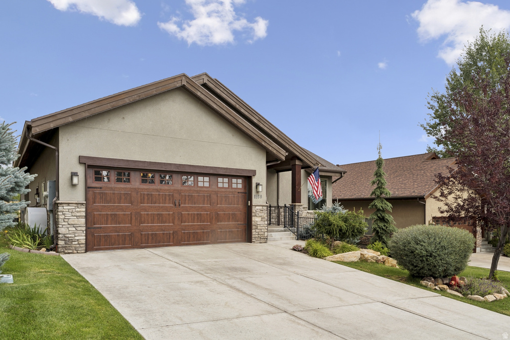 Craftsman-style house featuring stone siding, a garage, stucco siding, and concrete driveway