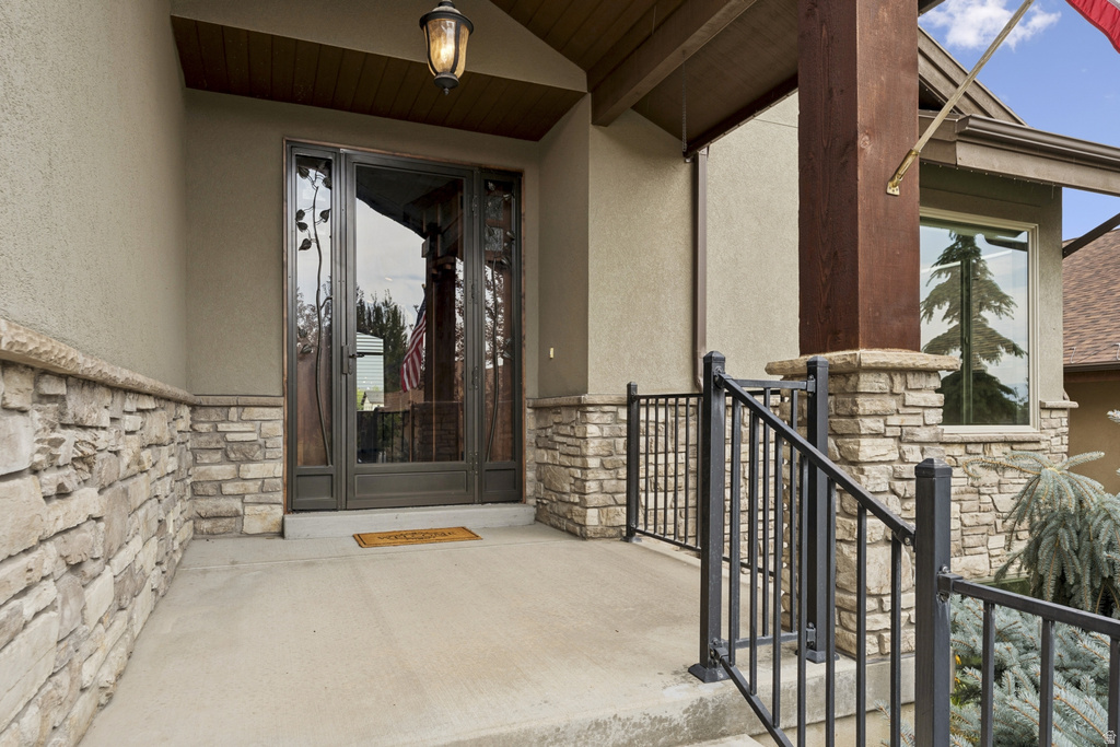 Doorway to property with stone siding, stucco siding, and a patio area