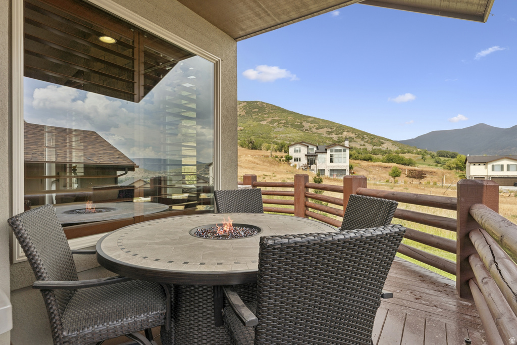 Deck featuring a fire pit, a mountain view, and outdoor dining area