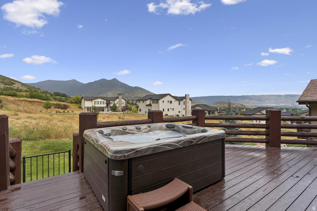 Wooden deck featuring a hot tub, a mountain view, and a residential view