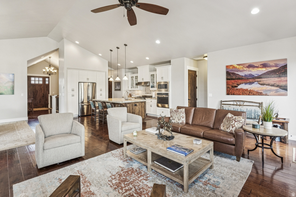 Living room featuring suspended lighting, dark wood finished floors, a ceiling fan, and vaulted ceiling