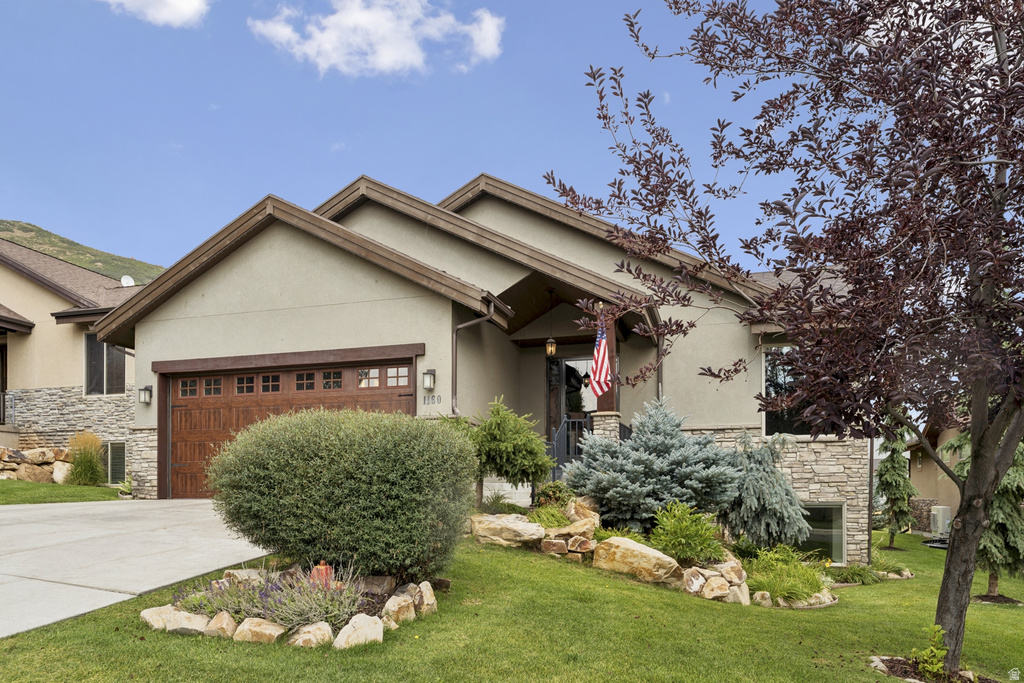 View of front of house with stone siding, a garage, stucco siding, and concrete driveway