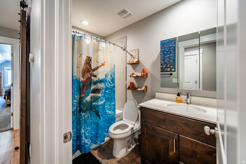 Bathroom with vanity, dark wood-style floors, and shower / bath combo with shower curtain