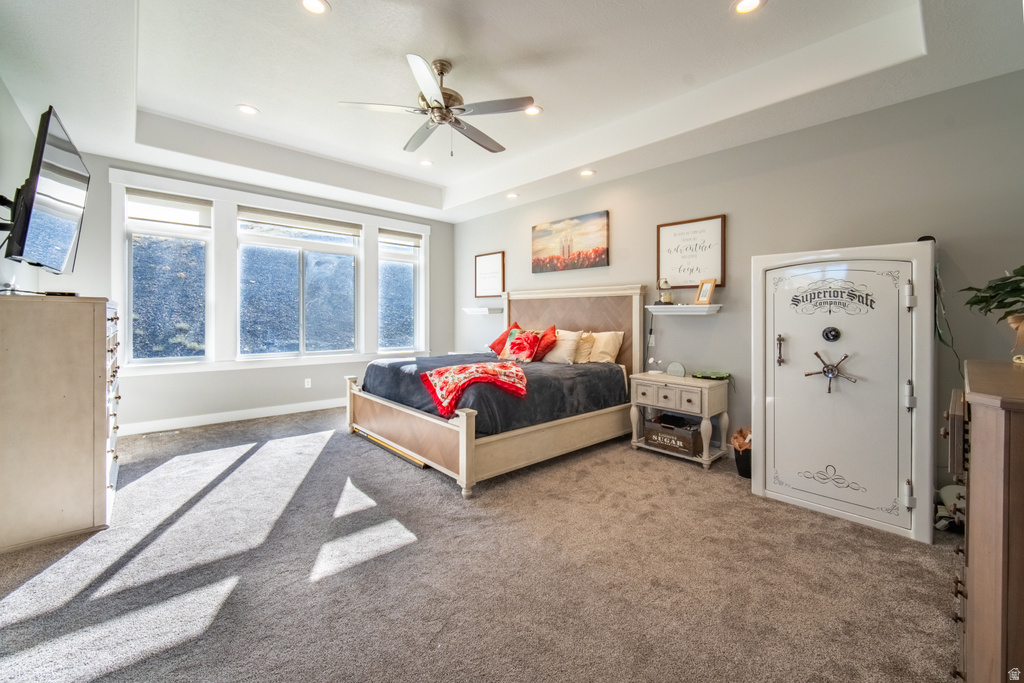 Carpeted bedroom featuring a tray ceiling, ceiling fan, and recessed lighting