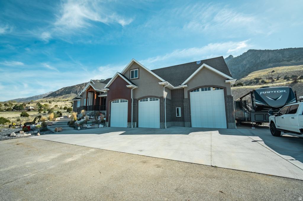 View of front of home with a mountain view, stucco siding, concrete driveway, and a garage