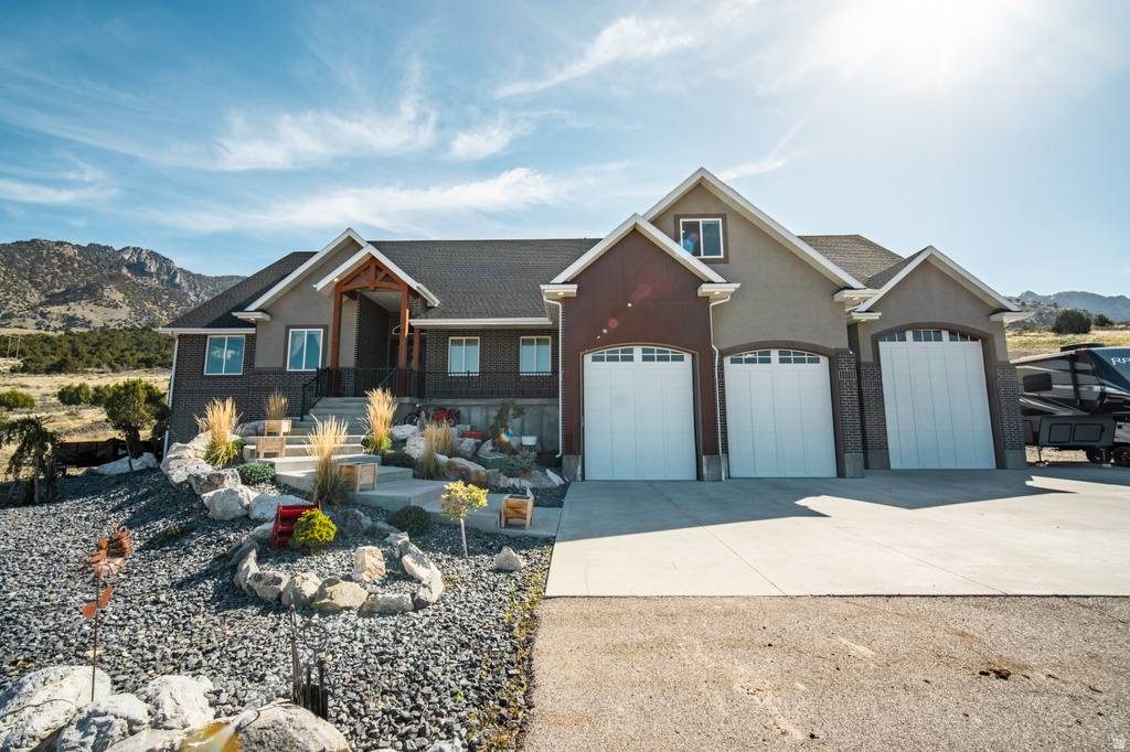 Craftsman house featuring concrete driveway, a mountain view, stucco siding, an attached garage, and a porch