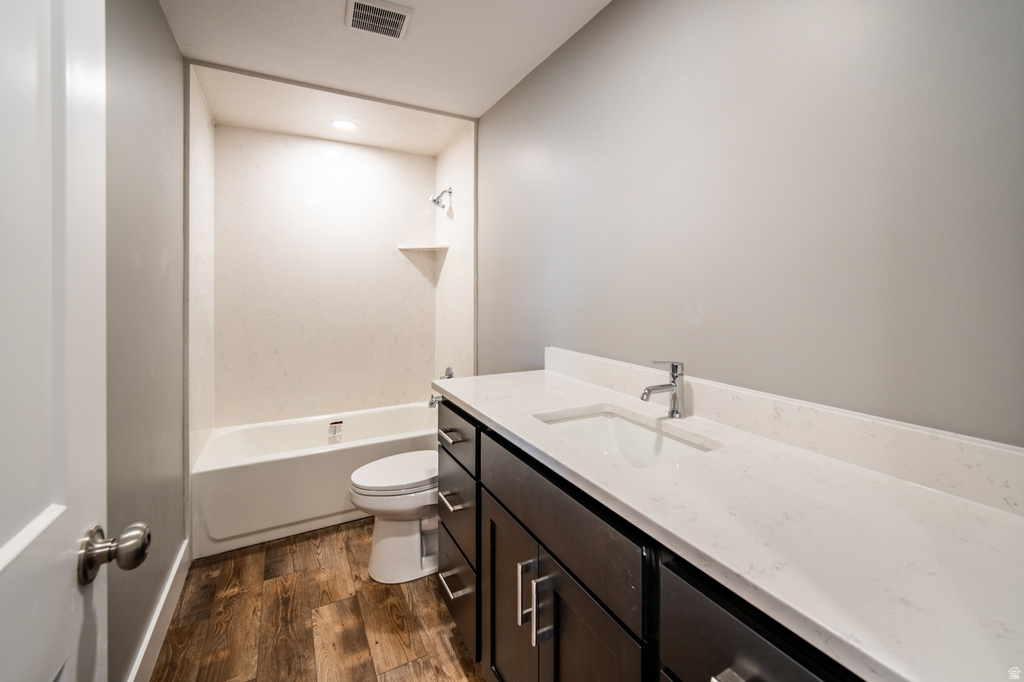 Full bathroom with vanity, dark wood-type flooring, bathing tub / shower combination, and recessed lighting
