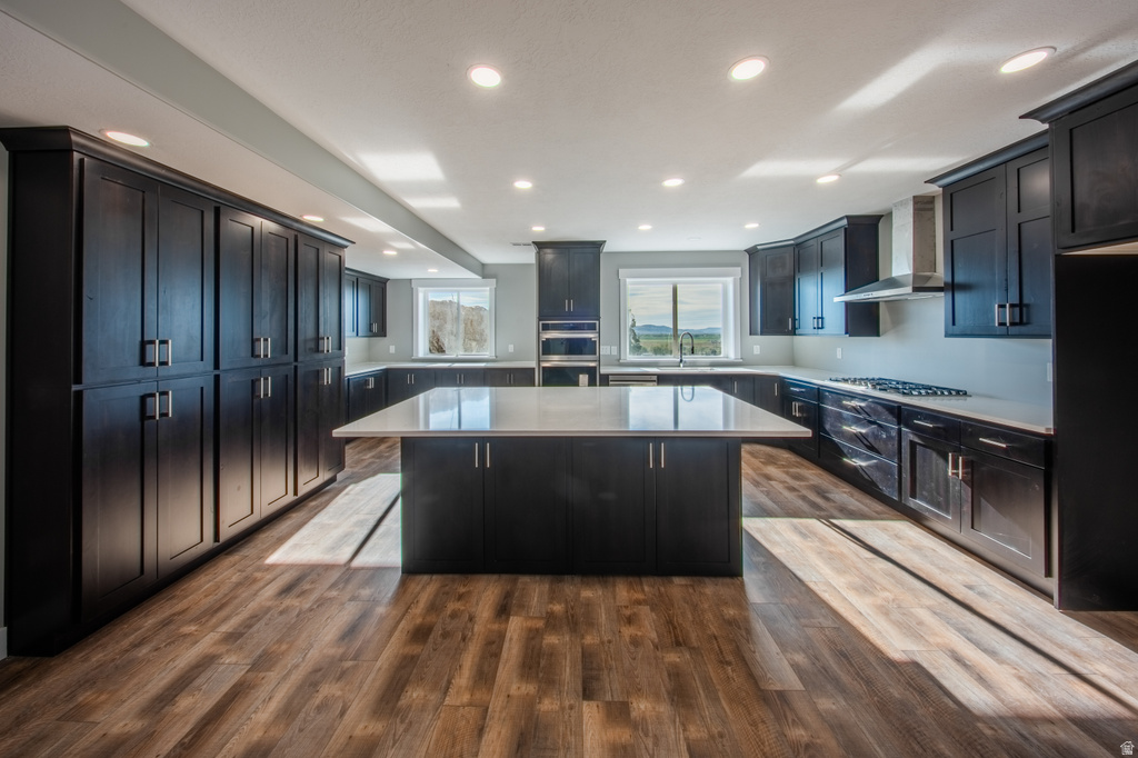 Kitchen featuring a kitchen island, dark wood-style floors, recessed lighting, stainless steel appliances, and light stone counters