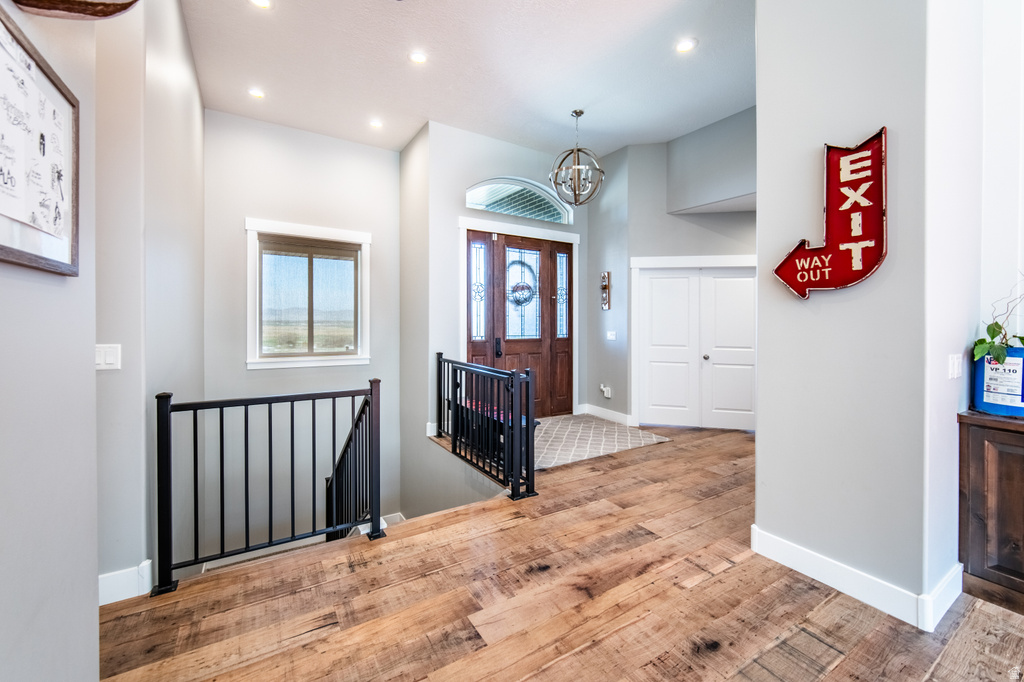 Foyer entrance with hanging lights, light wood-type flooring, and a high ceiling