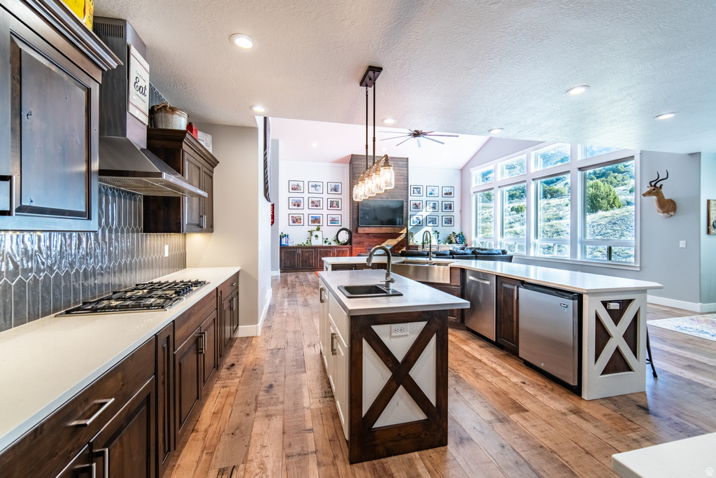 Dual tone kitchen with light wood finished floors, dual tone cabinets, stainless steel appliances, light stone countertops, and open floor plan