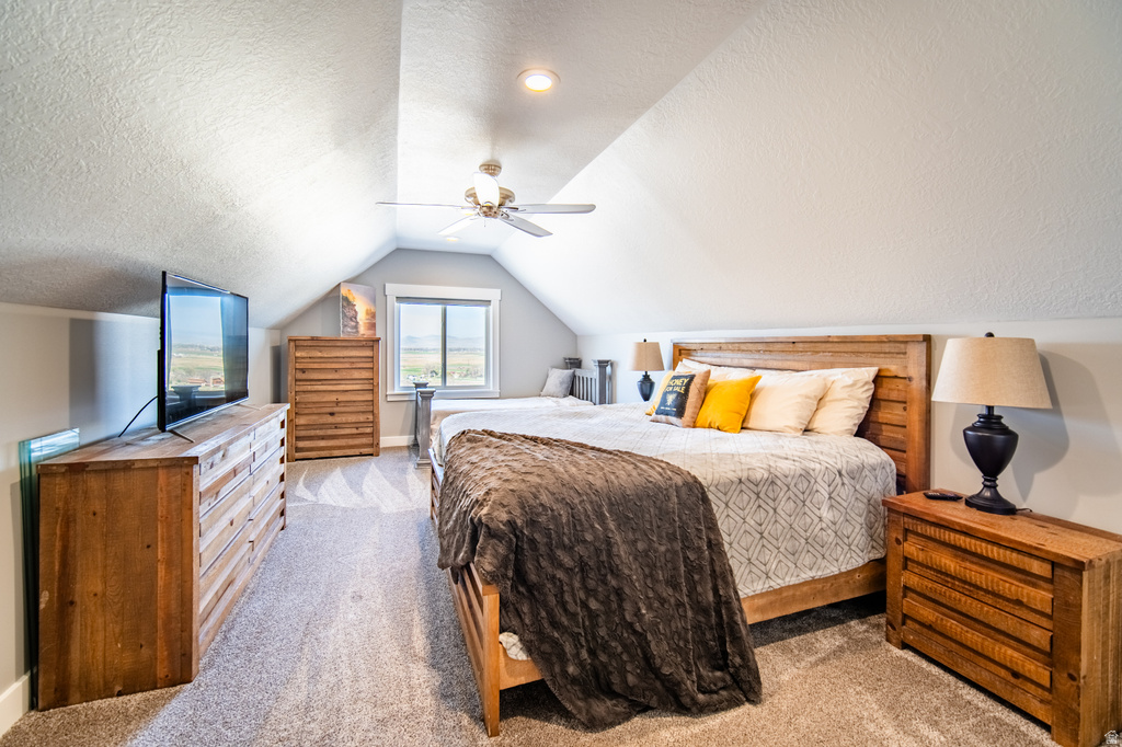 Bedroom featuring a textured ceiling, light carpet, and a ceiling fan