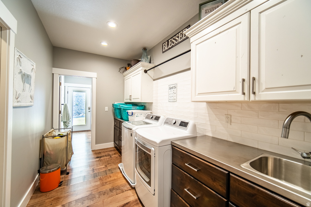 Laundry room featuring washer and dryer, cabinet space, light wood-style flooring, and recessed lighting
