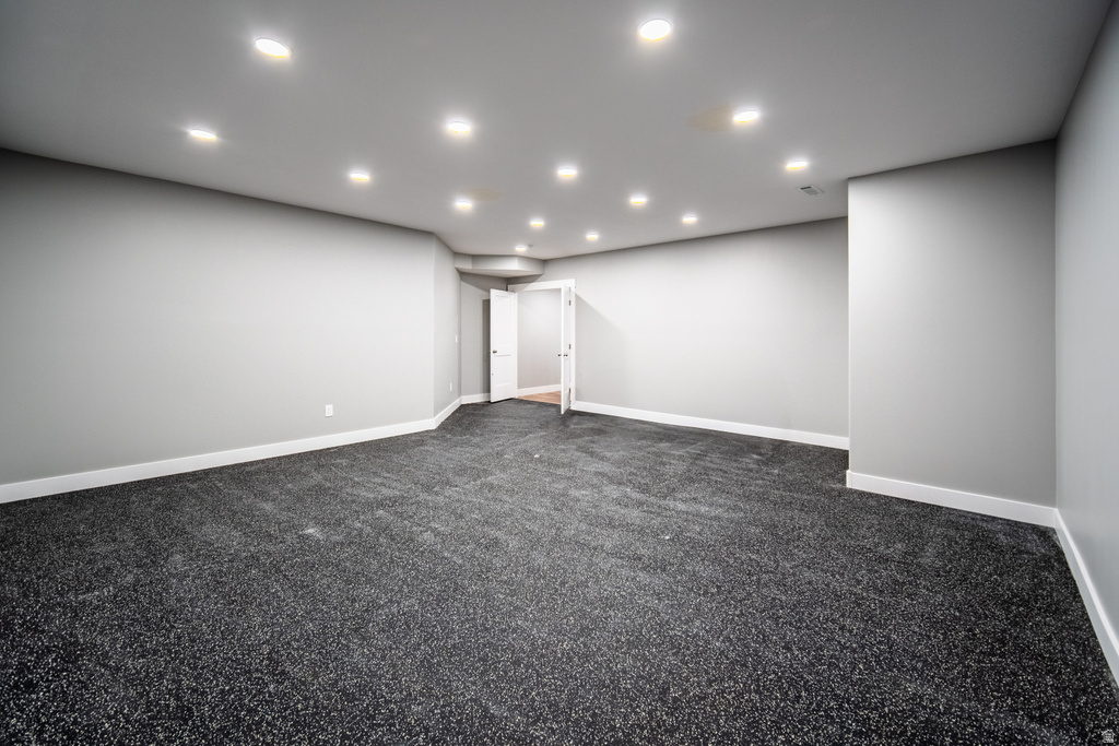 Unfurnished room with dark colored carpet and recessed lighting