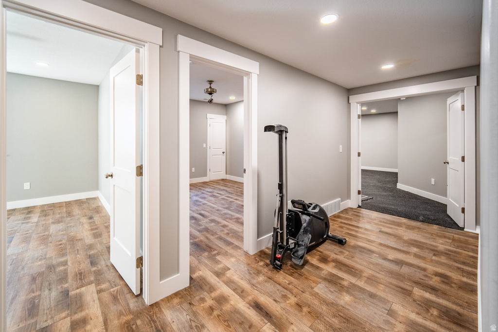 Exercise room with light wood-type flooring and recessed lighting