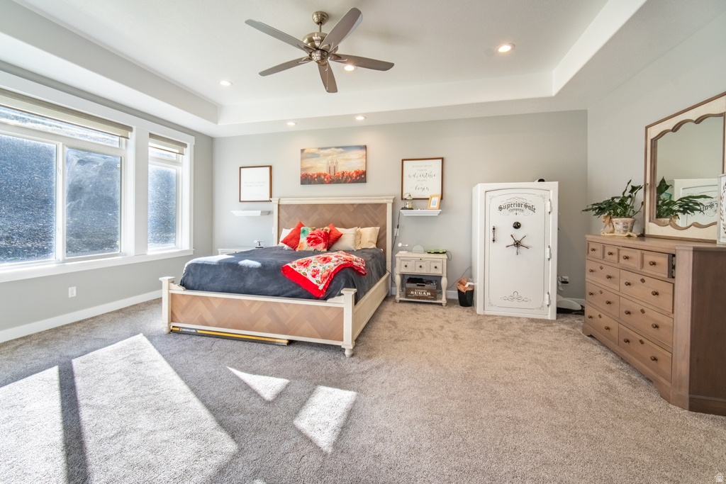 Bedroom featuring light colored carpet, a raised ceiling, a ceiling fan, and recessed lighting