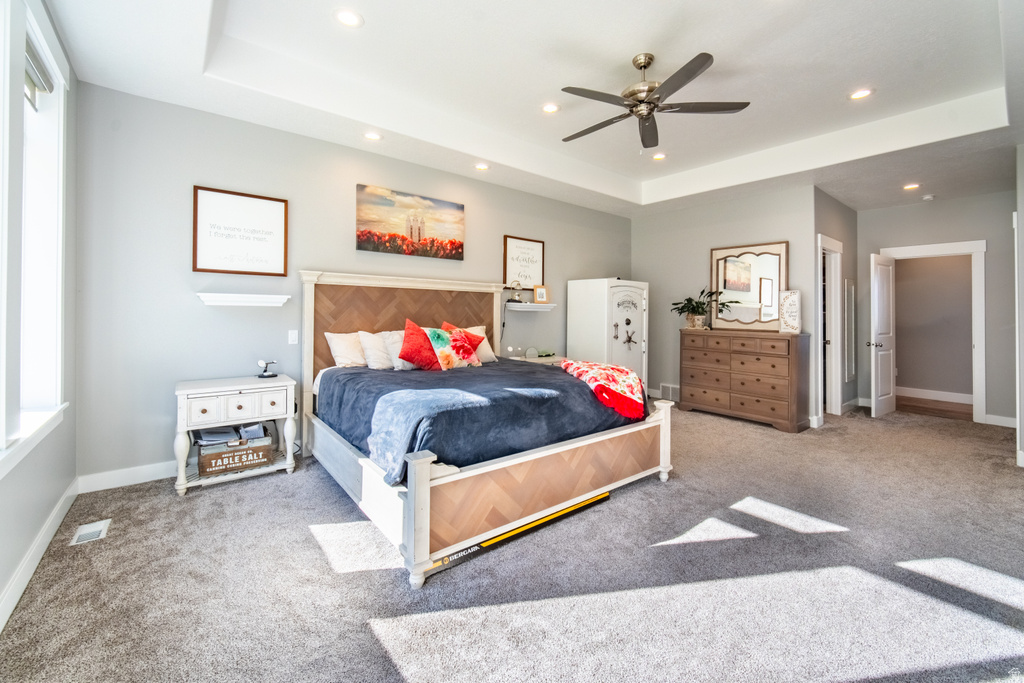 Bedroom with light colored carpet, ceiling fan, recessed lighting, and a tray ceiling