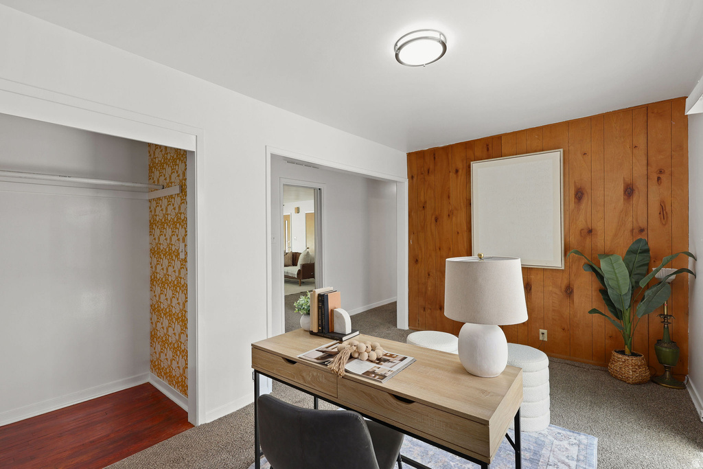 Carpeted room featuring a wood panel accent wall, a flush-mount ceiling light, and a built-in closet with wood-finish flooring