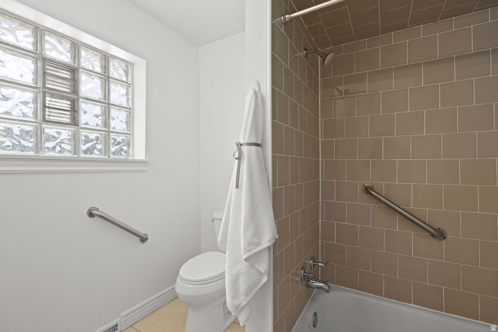 Full bathroom featuring a glass block window, a bathtub with a shower, subway tile surround, and grab bars