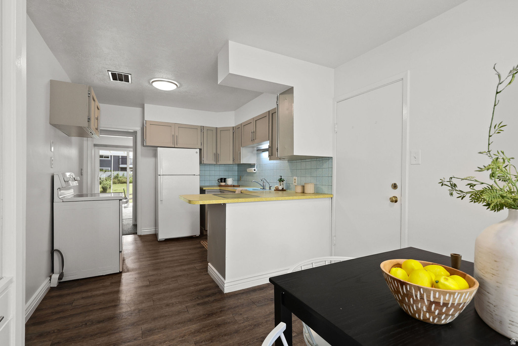 Kitchen featuring wood-finish flooring, light-toned cabinetry, light blue tile backsplash, a peninsula with a yellow countertop, and a built-in overhead light fixture