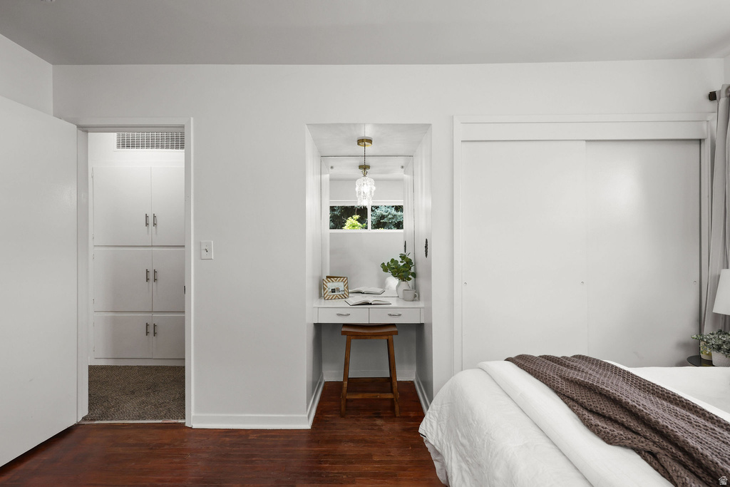 Recessed vanity niche with built-in desk, wood-finish flooring, sliding closet doors, built-in hallway cabinetry, and a ceiling-mounted light fixture