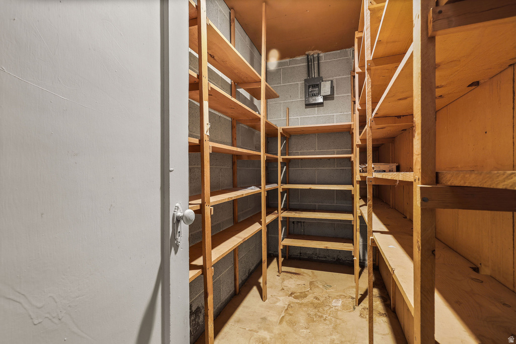 Dedicated storage room featuring extensive wood shelving, concrete block walls, and a concrete floor